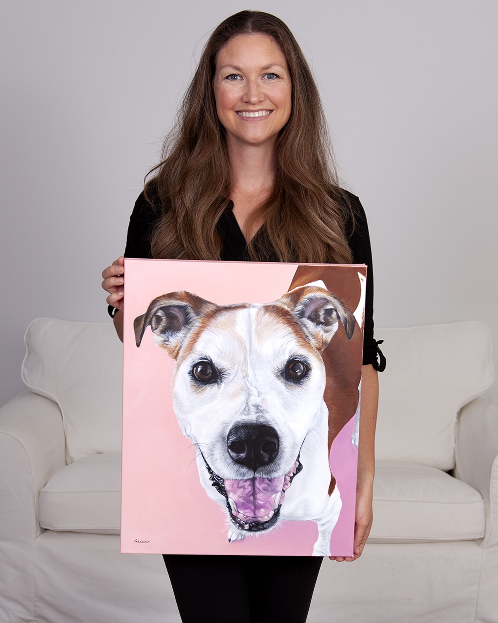 Fine arts painter Erica Eriksdotter holds her custom dog portrait of a pitbull boxer and hound mix