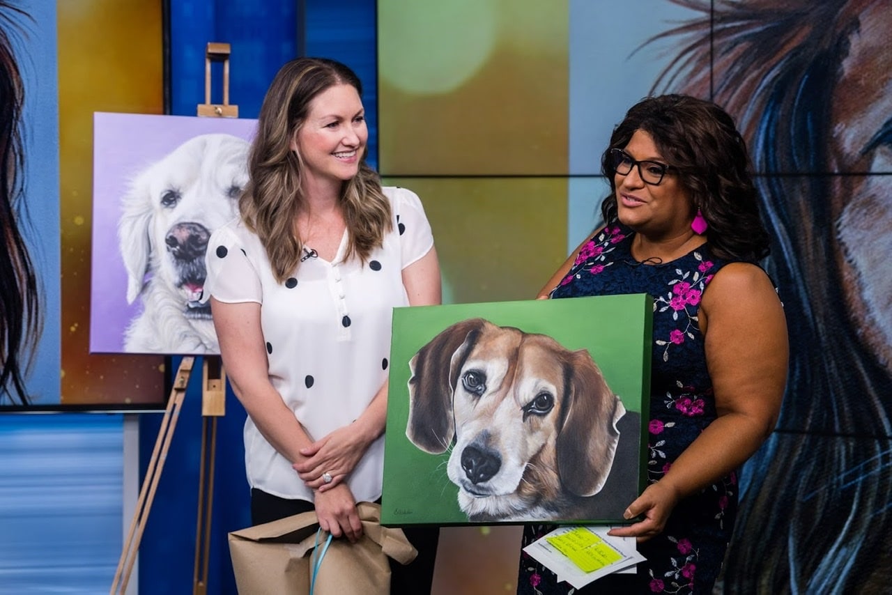 Fine arts painter Erica Eriksdotter sits by her easel with a custom painting of a black lab