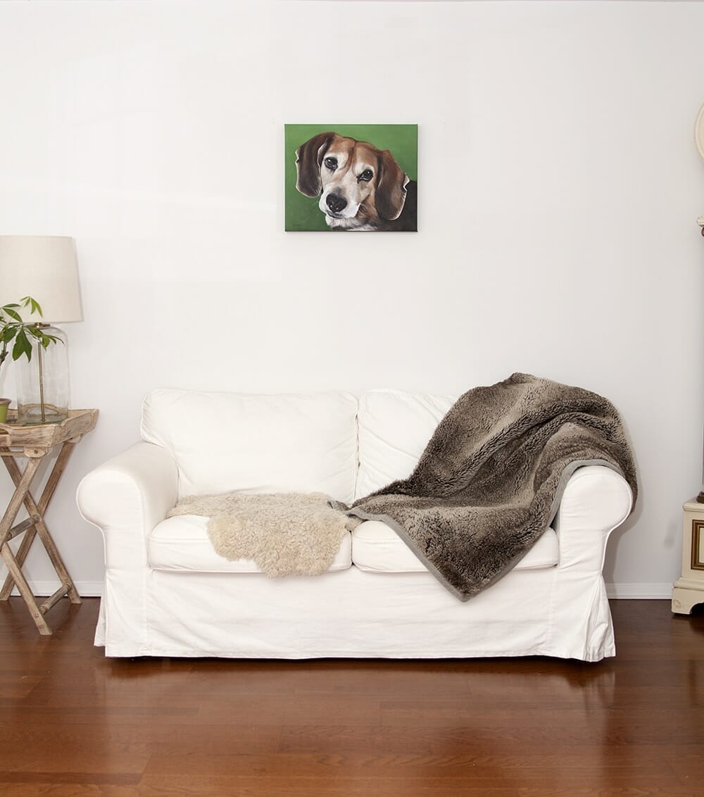 A custom dog portrait of a beagle by fine arts painter Erica Eriksdotter hangs above a white loveseat