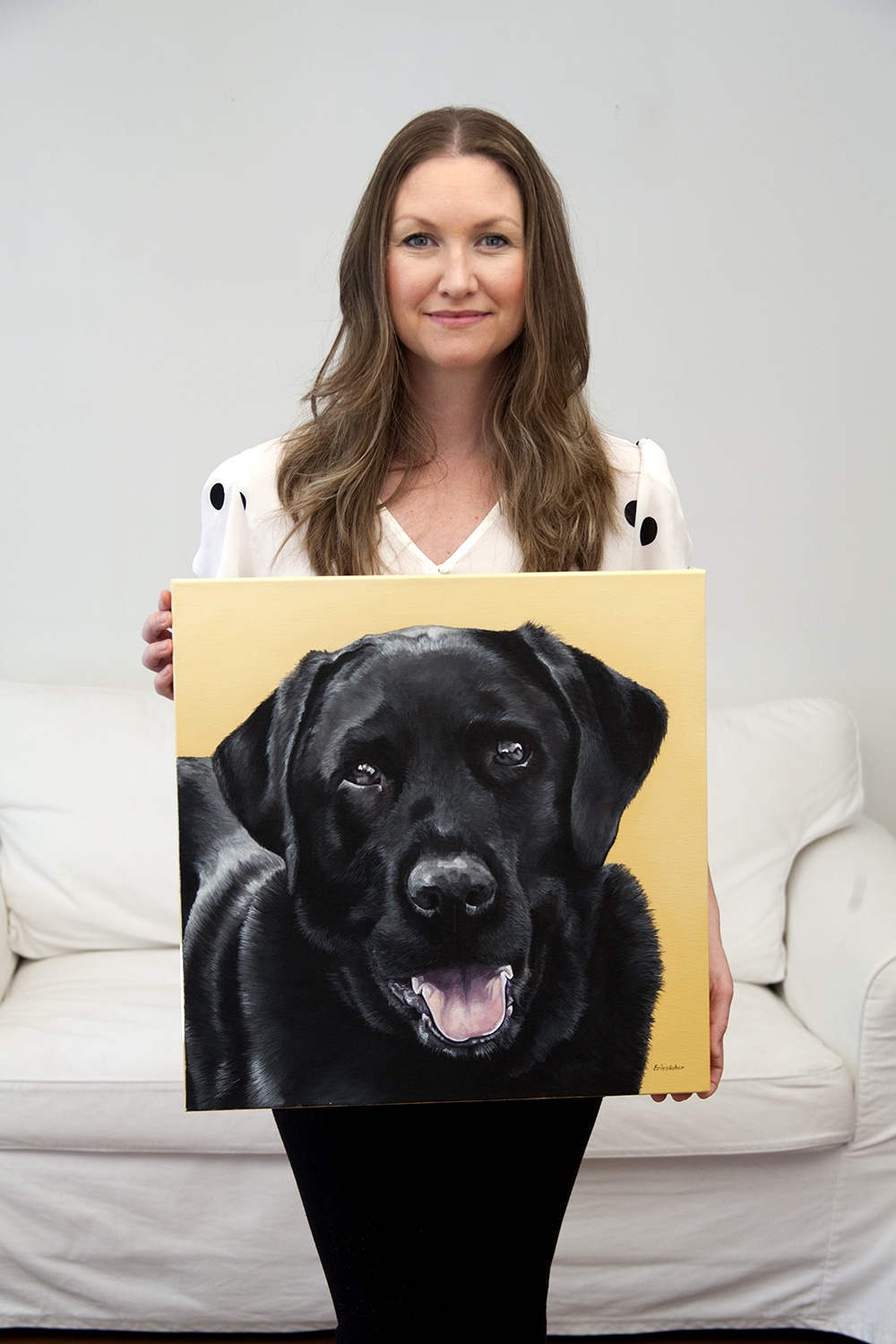 Erica Eriksdotter holding her custom dog portrait of a black labrador