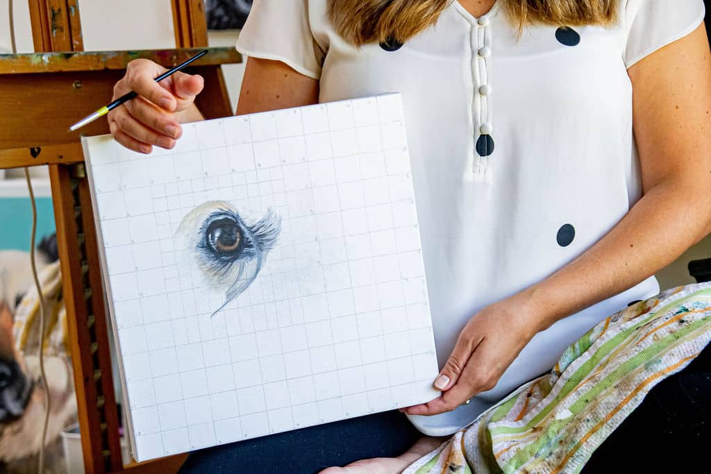 Erica Eriksdotter holding a canvas with a painted detailed animal eye, as the result of teaching her on-demand course 'How to Paint Soulful Eyes.'