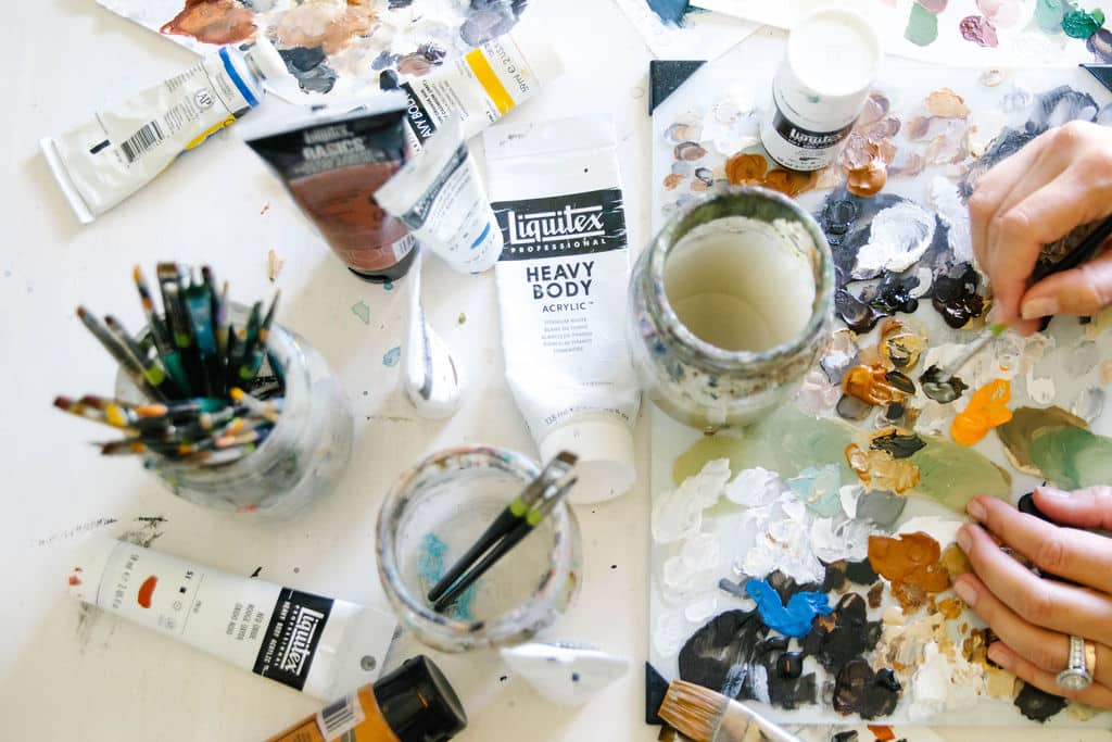 Erica Eriksdotter's painting supplies, including brushes and acrylic paints, used for creating custom pet portraits.